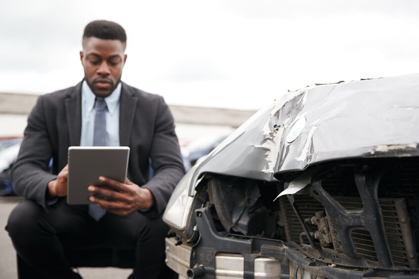 An insurance adjuster documenting damage to a vehicle